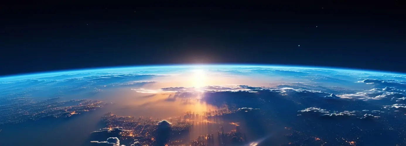 Earth's curvature from space with sunrise illuminating the atmosphere and a city below.