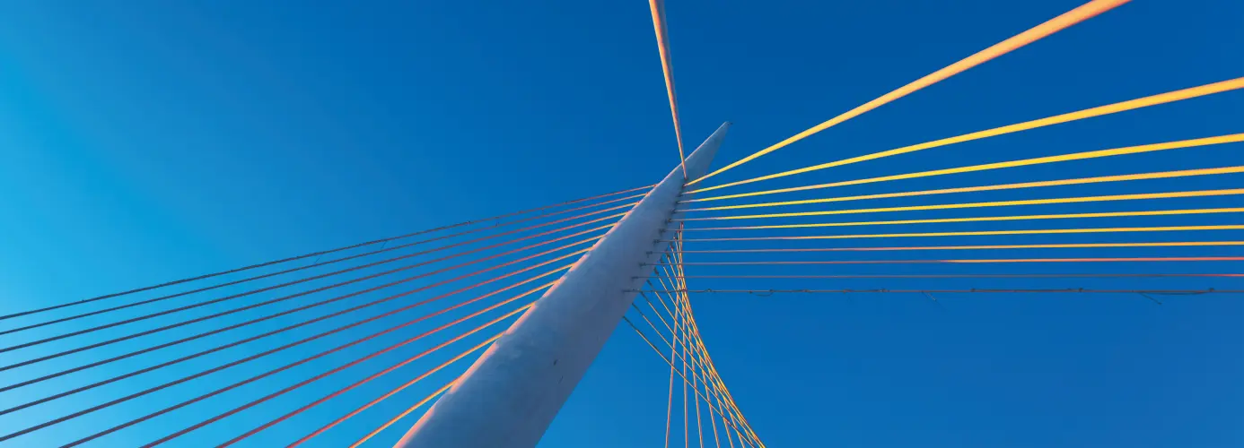 A bridge tower and suspension cables against a clear blue sky.