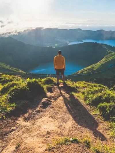 Person in yellow shirt overlooking mountain lakes