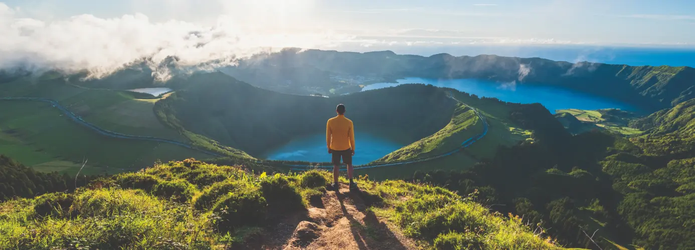 Person in yellow shirt overlooking mountain lakes