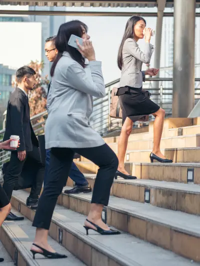 Business professionals ascending outdoor stairs, depicting a busy urban work environment.