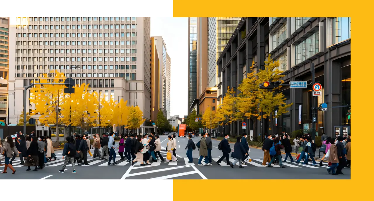 Busy city street with crowd crossing at crosswalk, surrounded by tall buildings and autumn trees with yellow leaves
