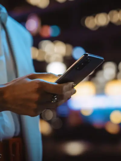 Hands holding smartphone with blurred lights in background