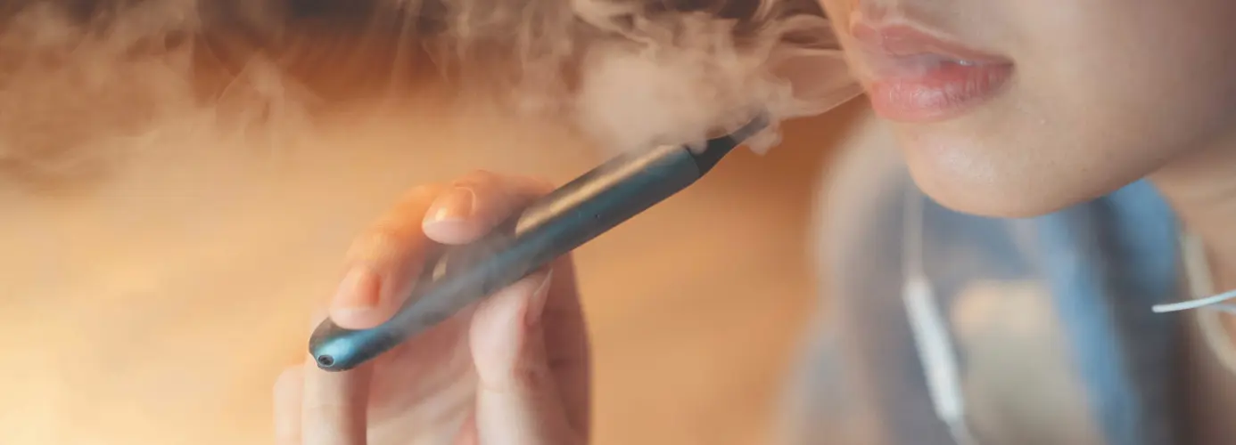 Close-up of person exhaling vapor from e-cigarette