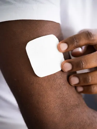 Hand applying a white patch to skin