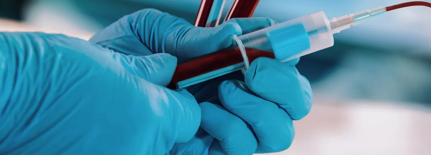 Gloved hands holding blood sample vials