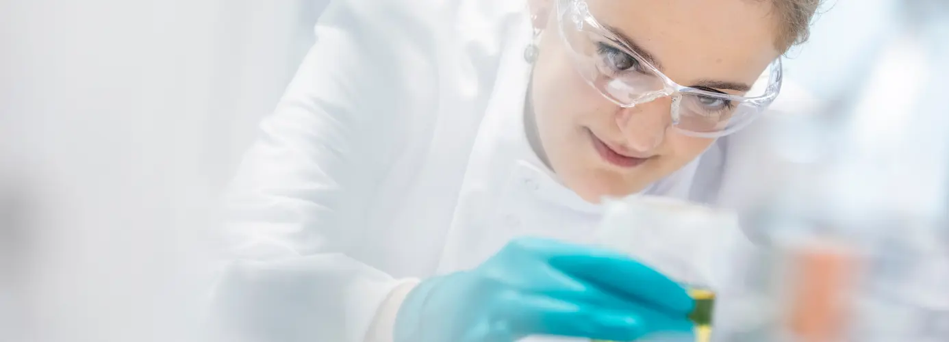 Person in lab coat examining test tube