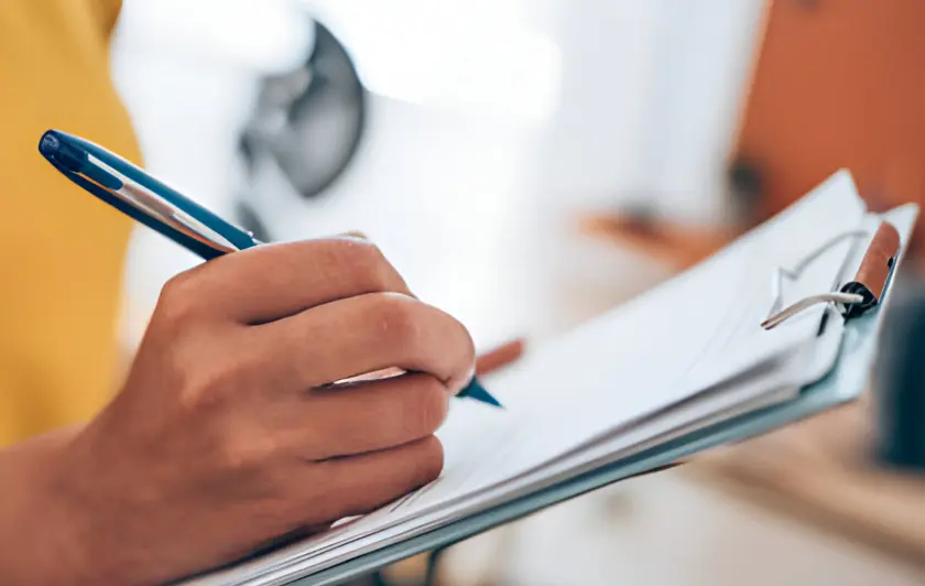 A person writing on a clipboard