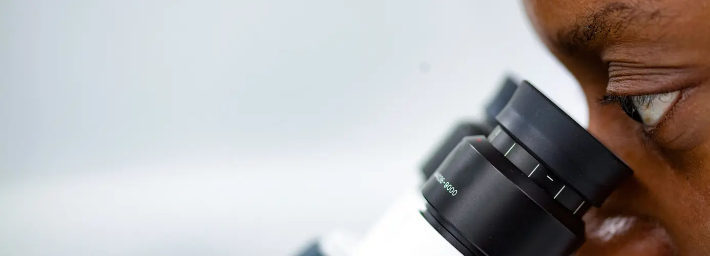 A close-up of a person looking through a microscope