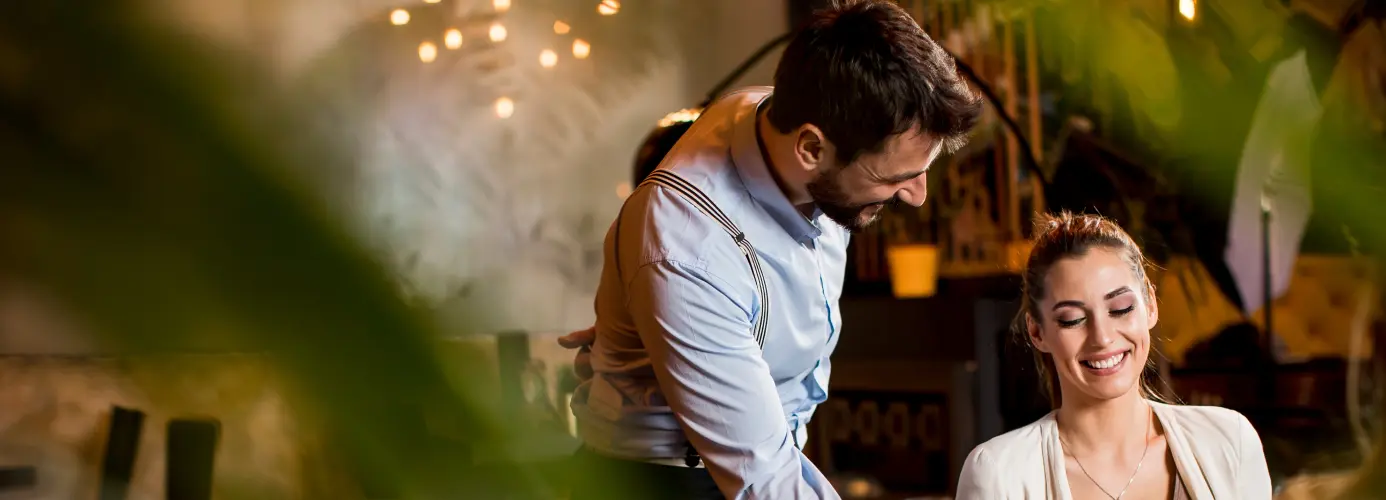 A waiter serving food to a woman in a restaurant