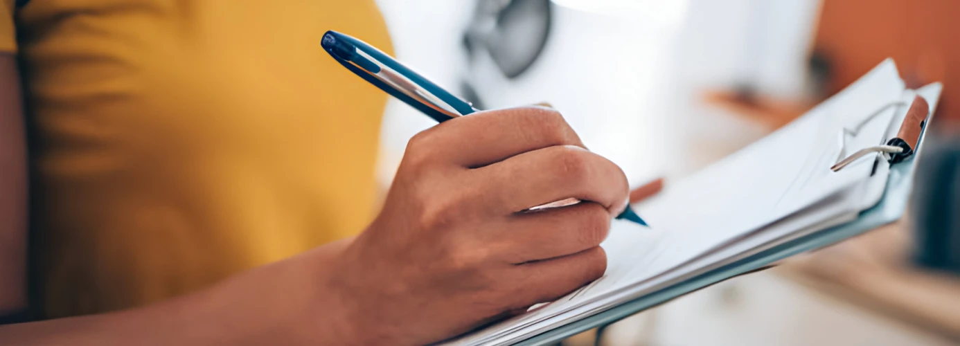A person writing on a clipboard