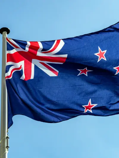 New Zealand flag waving against a blue sky.