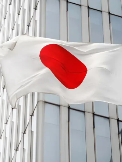 Japanese flag waving in front of a modern office building.