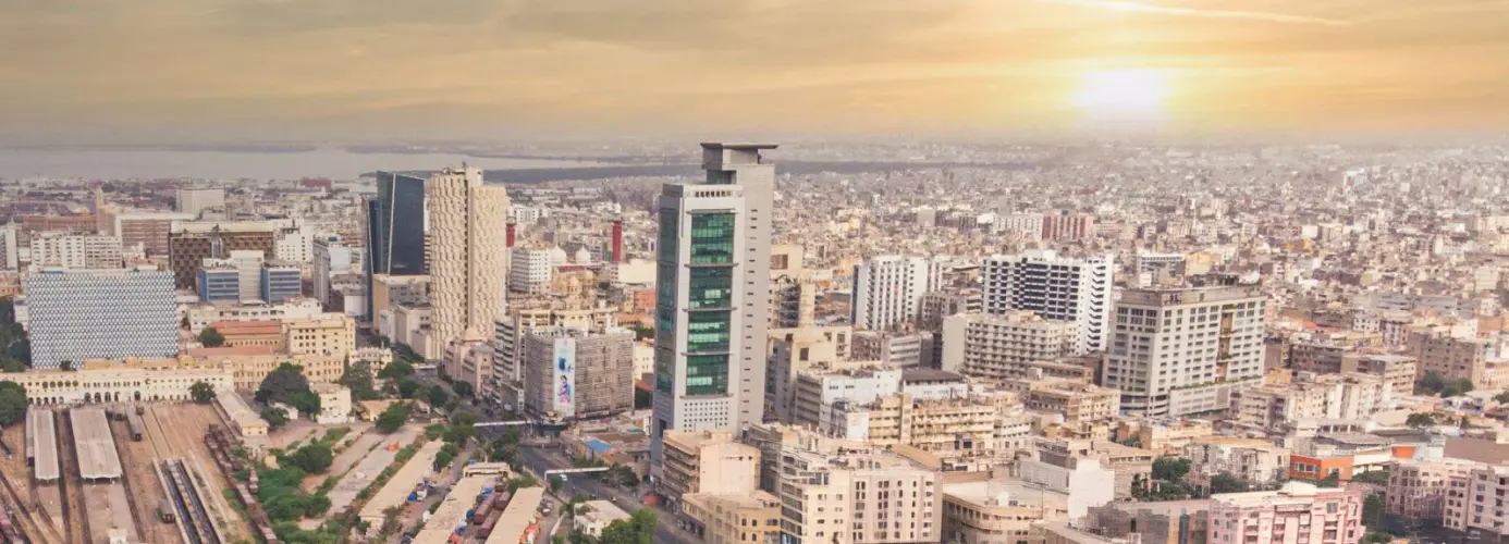 Aerial view of a densely populated city skyline with modern skyscrapers and buildings at sunset.
