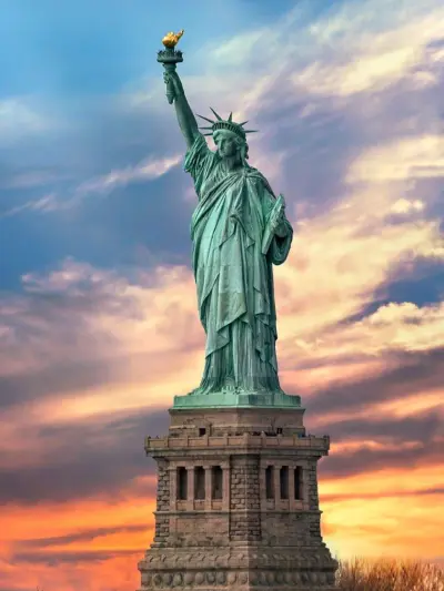 Statue of Liberty against a colorful sunset sky.