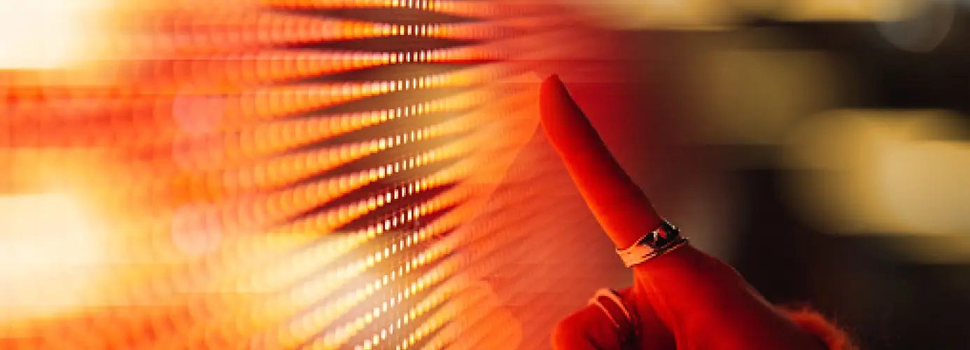 Close-up of a hand touching an illuminated surface with glowing lines.