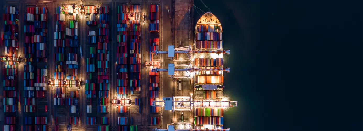 Aerial view of illuminated cargo ship loading colorful shipping containers at night