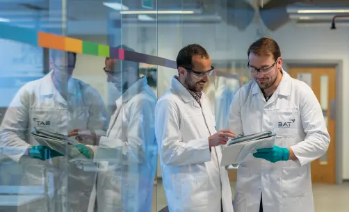 Scientists in lab coats examining data on clipboard