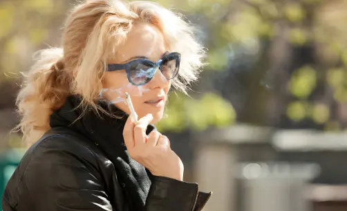 Woman with blonde hair smoking outdoors
