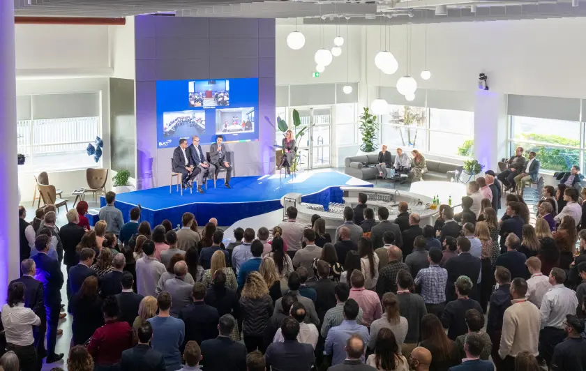 Corporate presentation with speakers on stage and large audience