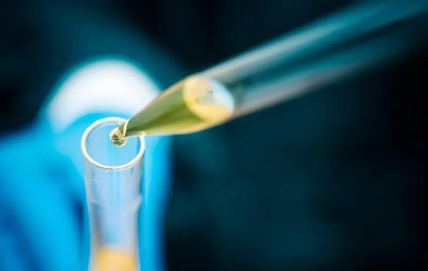 Pipette dropping liquid into test tube in laboratory