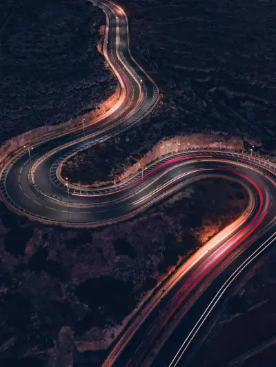 Winding mountain road with light trails at night
