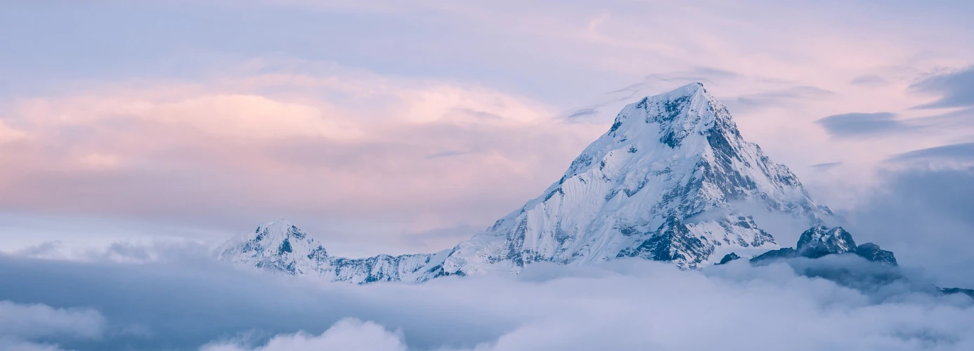 Snow-covered mountain peak above clouds at sunset